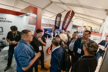 Interacción entre visitantes y expositores en el área de estands.